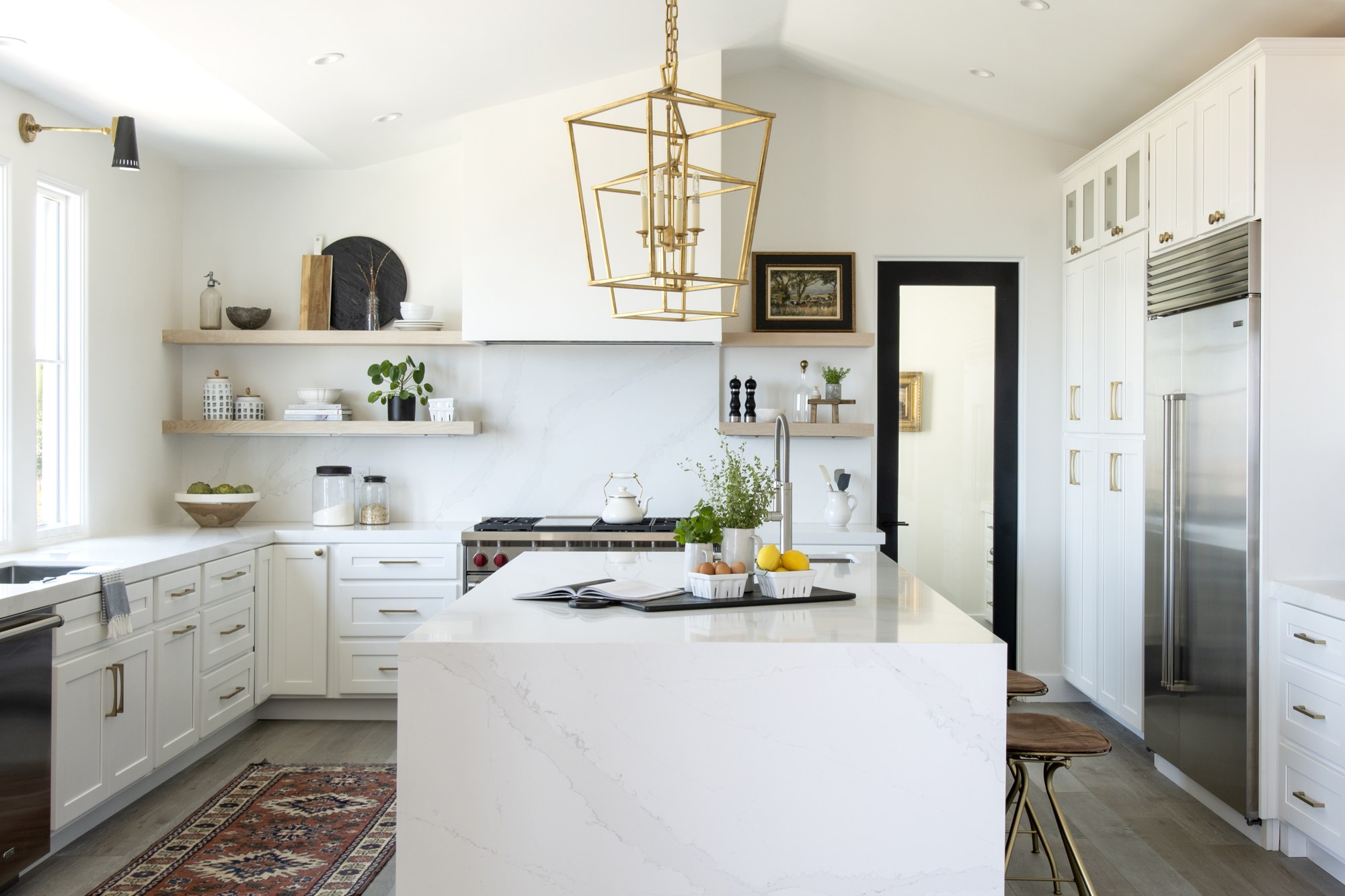 Bright M StudioHouse kitchen with white cabinetry, brass pendant lighting and patterned runner
